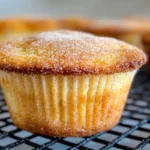 Cinnamon sugar French Toast muffins hearty Delish, topped with a dusting of cinnamon sugar, placed on a black wire cooling rack.